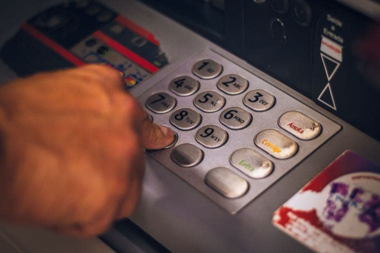 A hand pressing a button on an ATM keypad