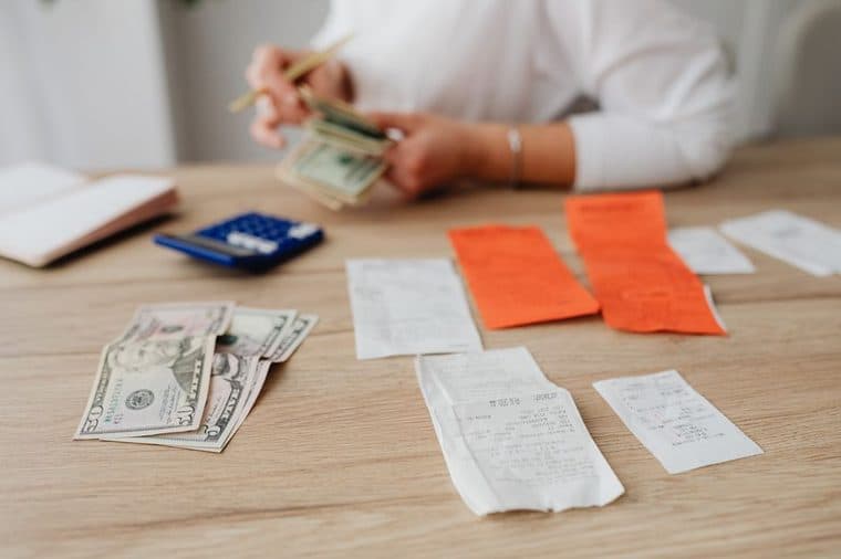 A person working out a household budget with a calculator and bills