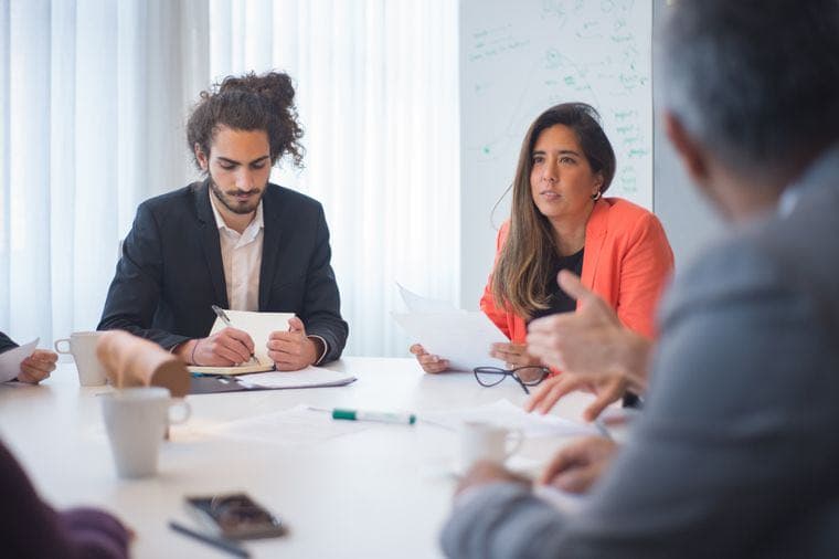 A business owner delegating work in a team meeting