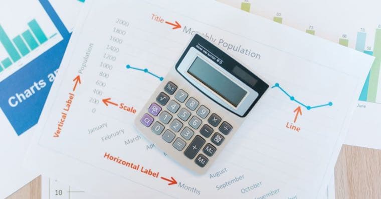 A calculator and property documents beside two wedding rings