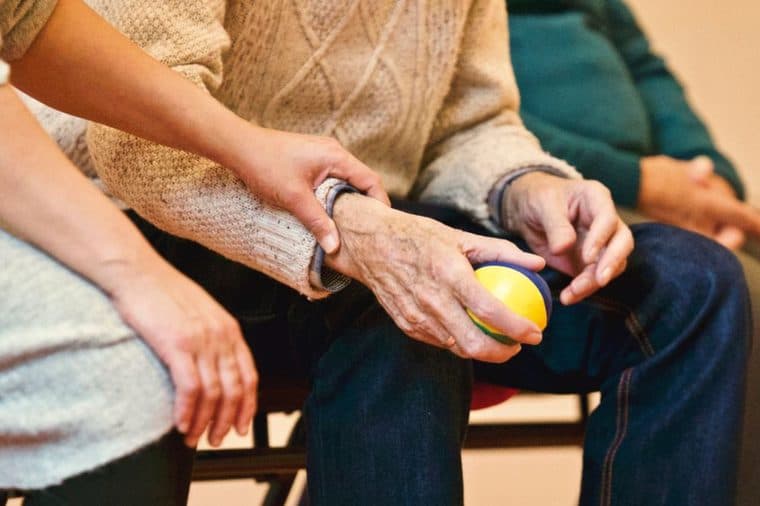 A carer holding the hand of an elderly person