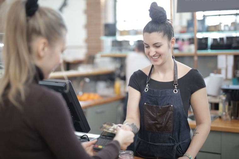 A casual retail worker helping a customer at a checkout in Australia