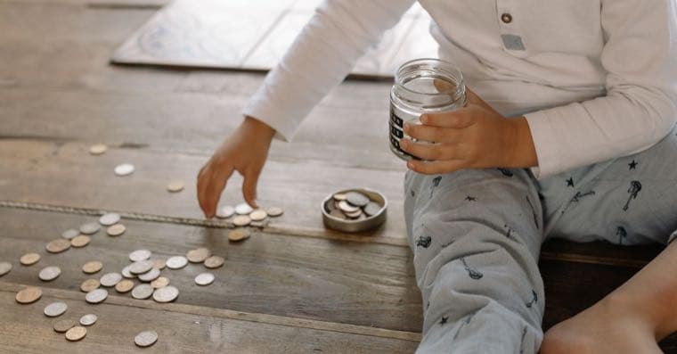 A child putting a coin into a piggy bank