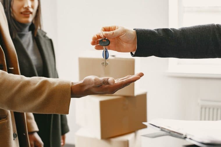 A person being handed keys with moving boxes in the background