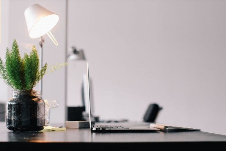 A calm, softly lit desk with a phone, suggesting a pause before an online purchase