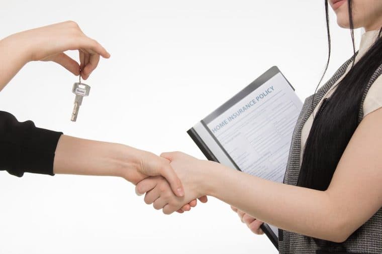 A person signing property purchase documents at a desk
