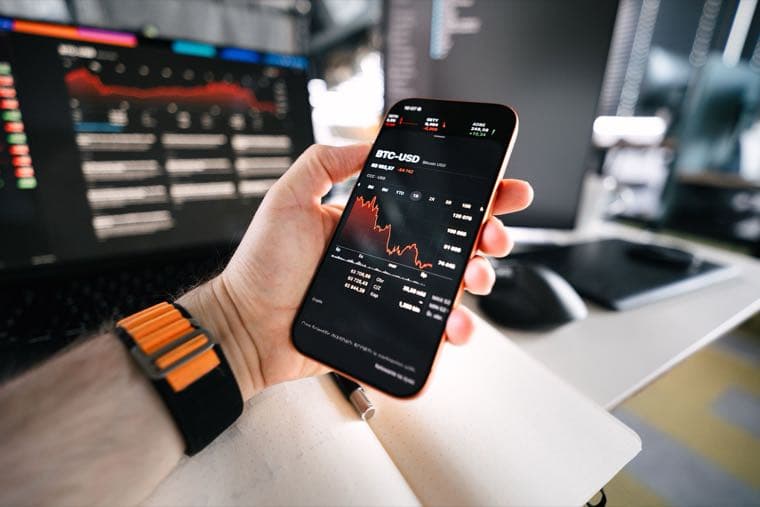 A hand holding a smartphone showing a crypto trading app