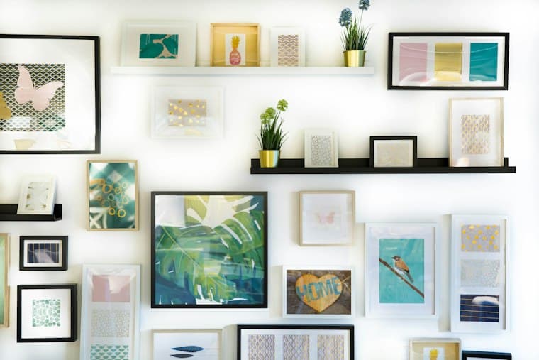 A white wall covered in many small framed prints arranged as one display