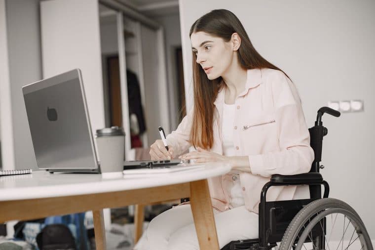 A person using a wheelchair working at a laptop at home