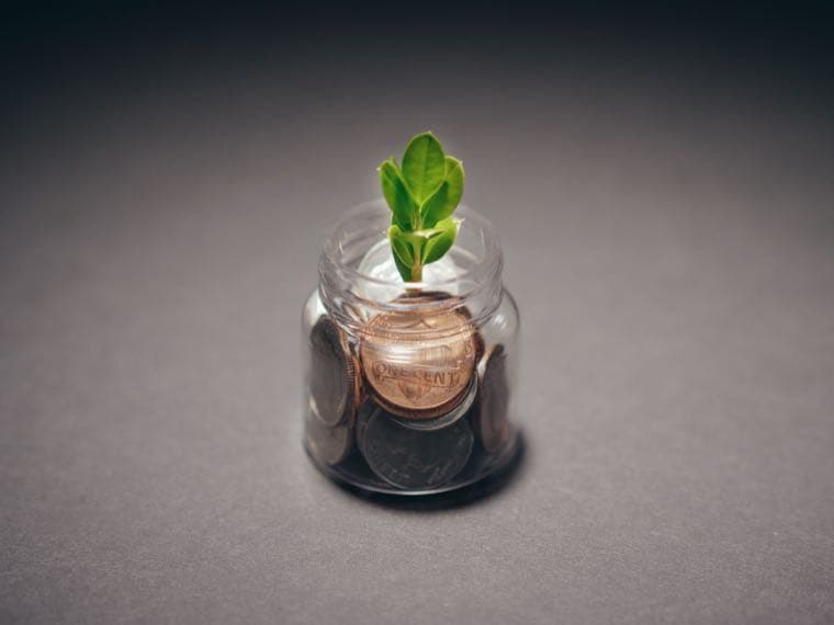A growing snowball of coins, representing dividends compounding through a reinvestment plan