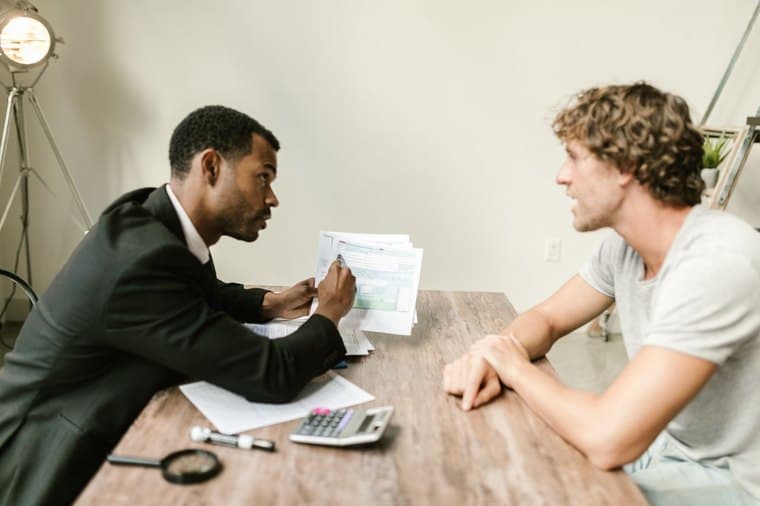 A financial adviser discussing paperwork with a client at a desk