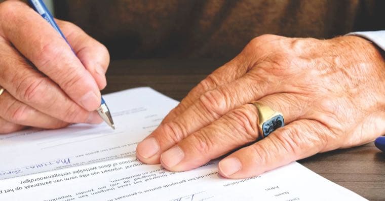 Two people signing a legal document together at a table