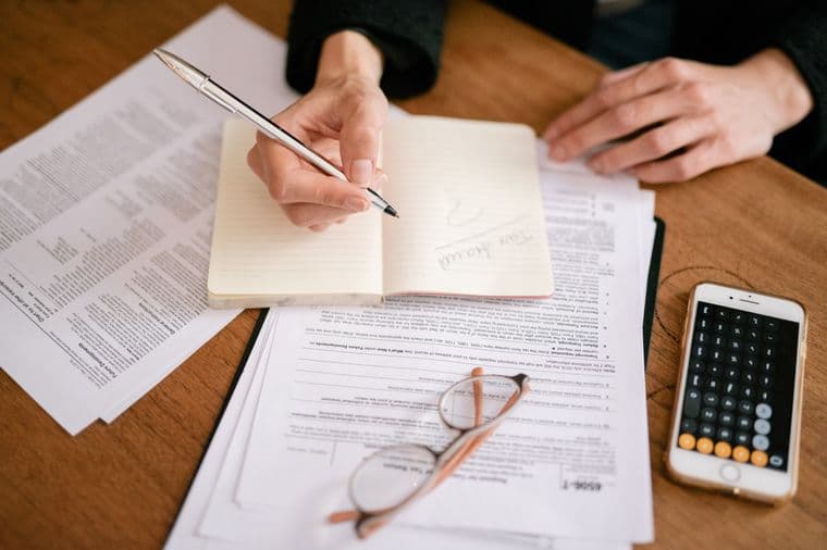 A person annotating tax documents at a desk with a calculator