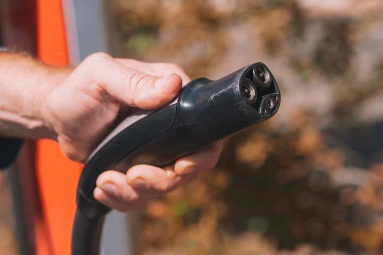 A hand holding an electric vehicle charging plug