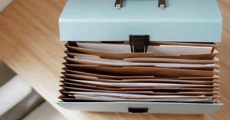 A person organising paperwork and folders at a home desk