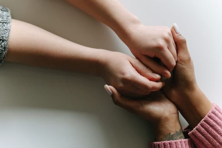 A supportive hand resting reassuringly on another person's hands