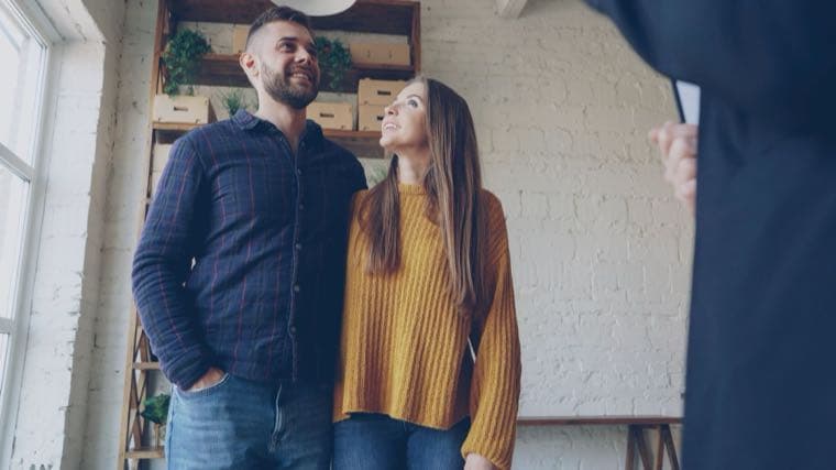 A young couple happily looking at their new home, representing the First Home Guarantee scheme