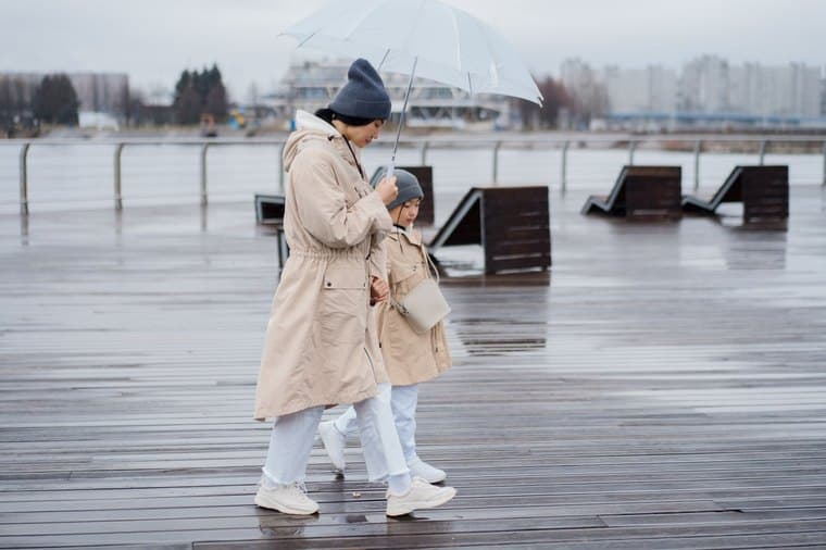 A parent and child walking together under an umbrella