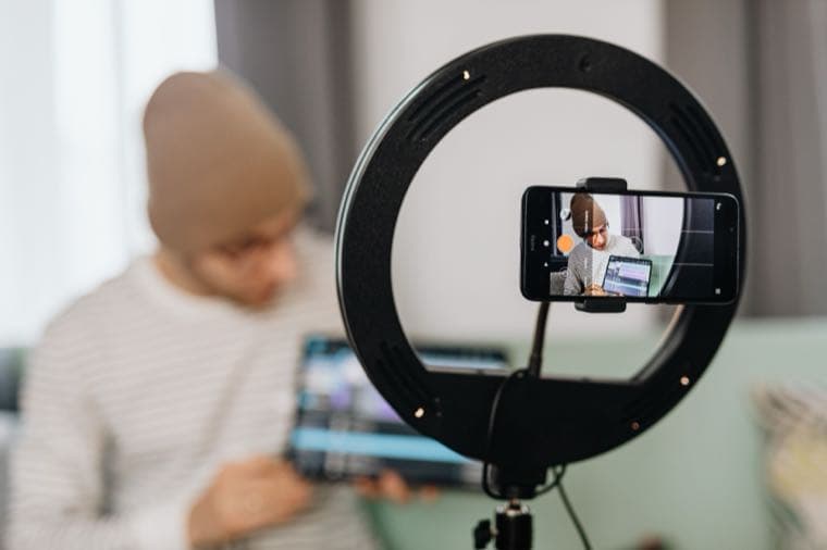 A creator filming themselves with a ring light and smartphone