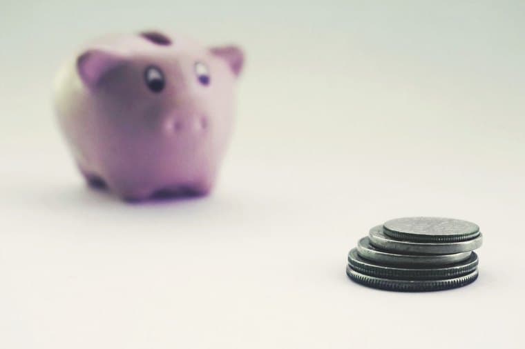 Stacked coins growing beside a piggy bank, representing regular monthly investing