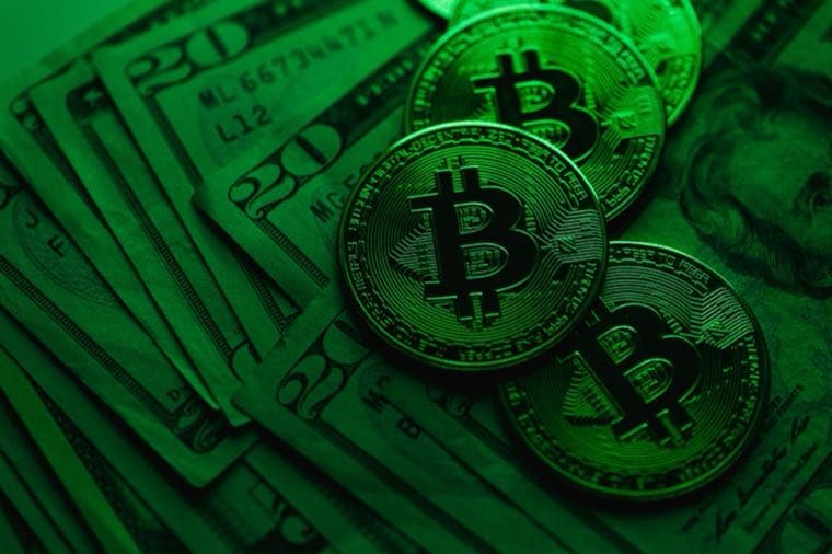 Physical Bitcoin coins resting on banknotes, tinted green
