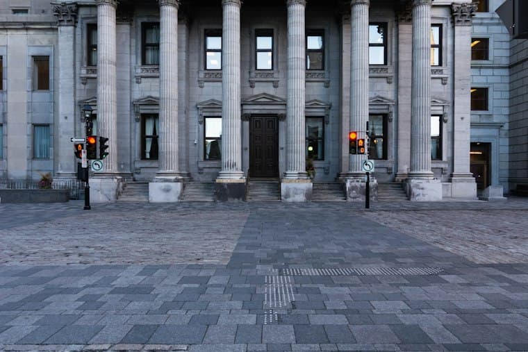 The columned stone facade of an old bank building seen across an empty plaza