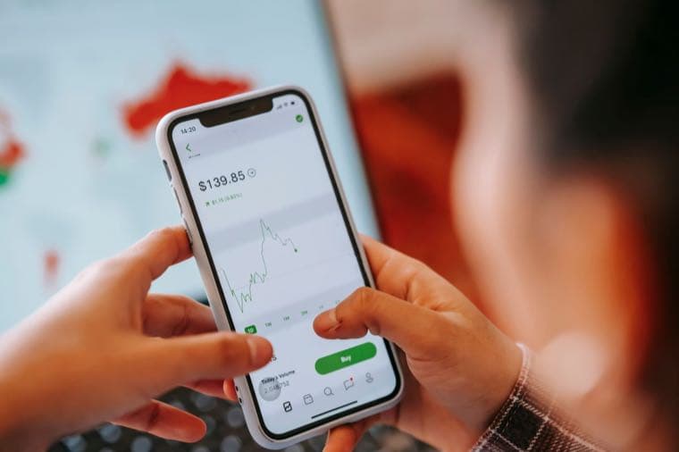 A phone showing a share trading app with a green Buy button