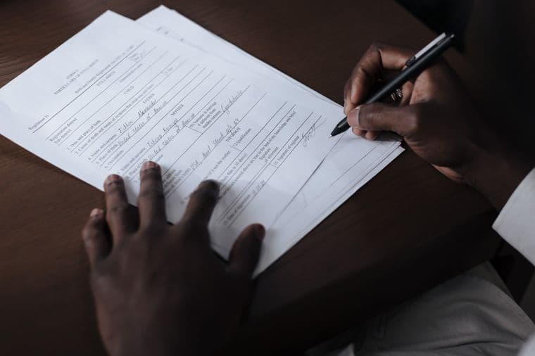 Hands filling in a paper form at a desk