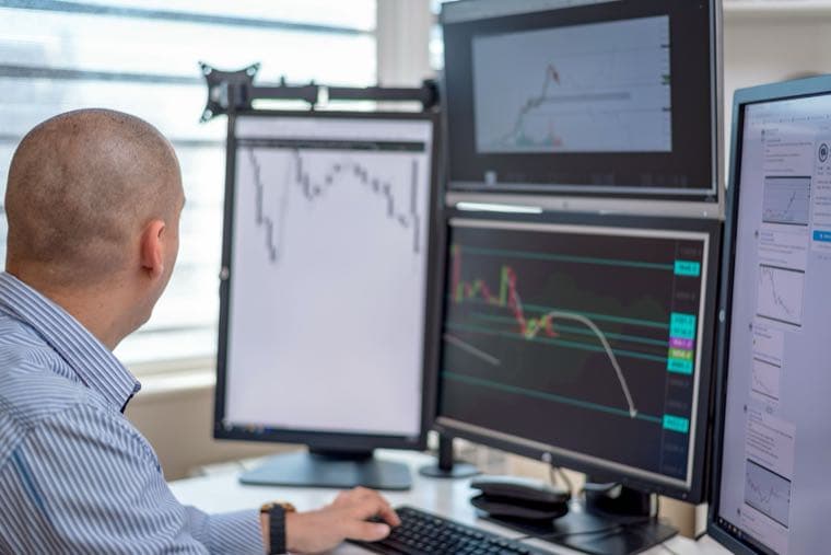 A trader watching crypto price charts across several monitors