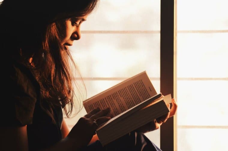 A person reading a book by a sunlit window