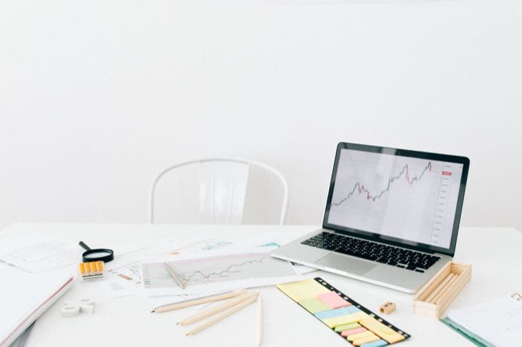 A laptop and stationery on a clean white desk set up for planning