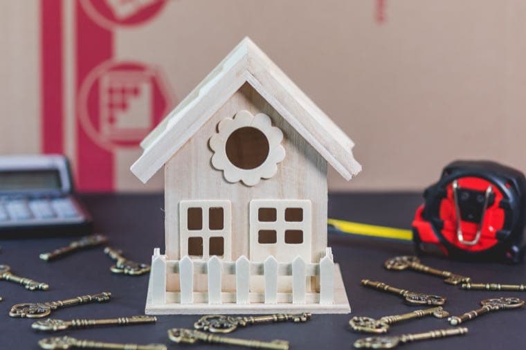 A wooden house model with old keys and a calculator on a desk