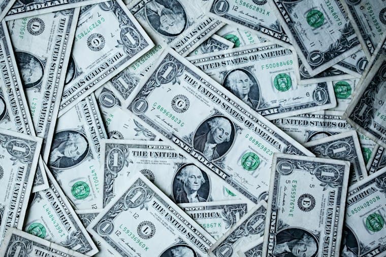 A scattered pile of United States one dollar notes filling the frame