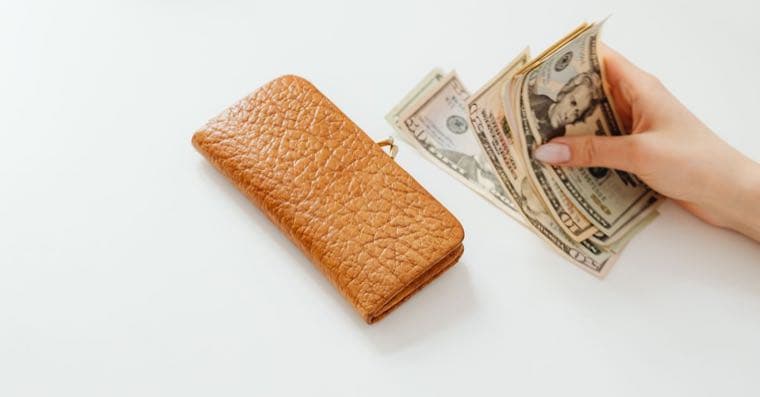 A person counting cash from a wallet