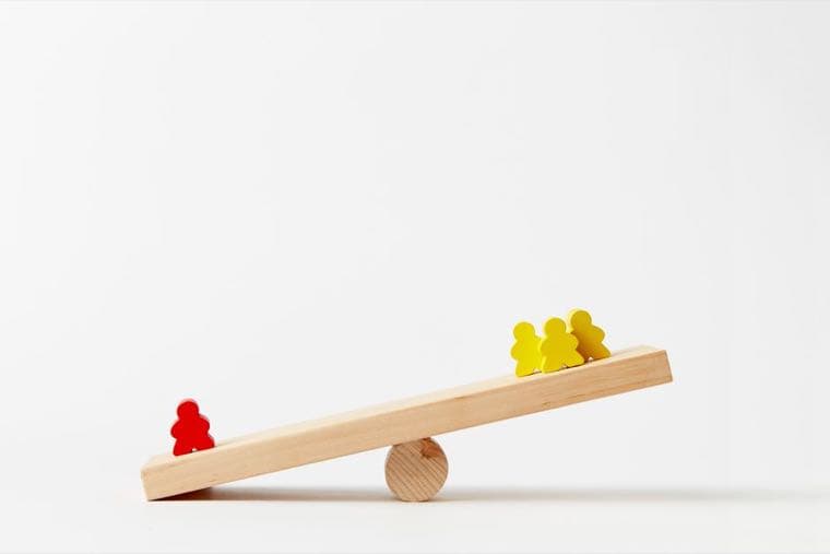 A wooden seesaw where one red figure on the low side outweighs three yellow figures on the other