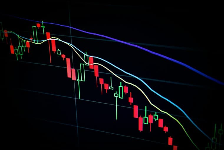 A candlestick price chart on a dark screen, trending downwards