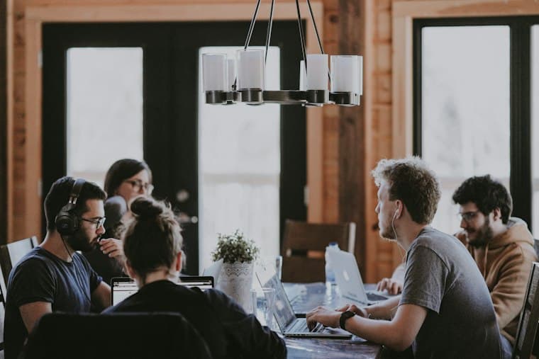 People working at laptops around a long shared table in a timber lined room