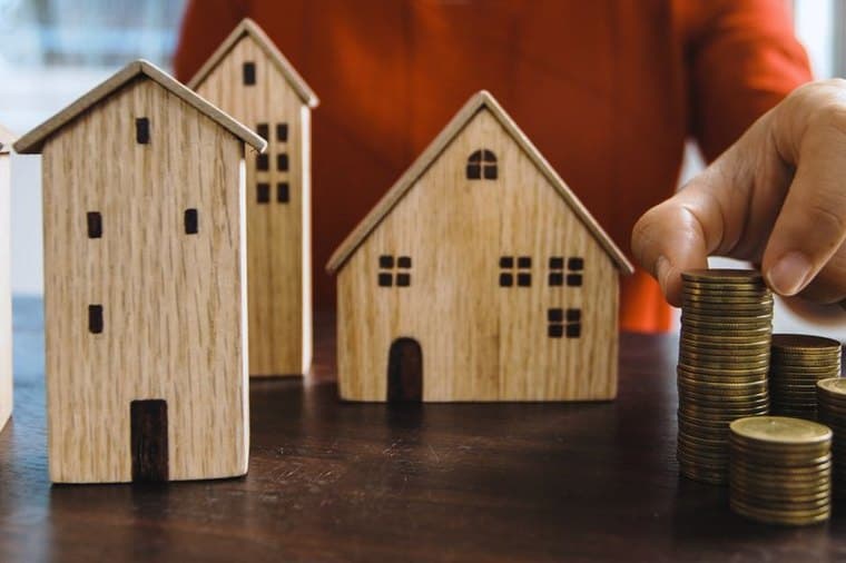 Model house beside stacked coins, representing the choice to repay a mortgage or invest