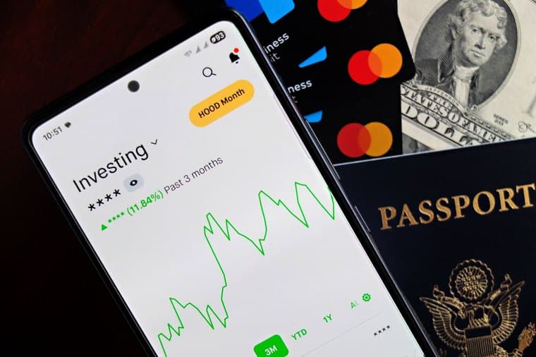 Investing app on a phone next to cards and cash, representing round-up micro-investing