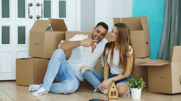 A couple with moving boxes in a new home, representing the rent vs buy decision in Australia