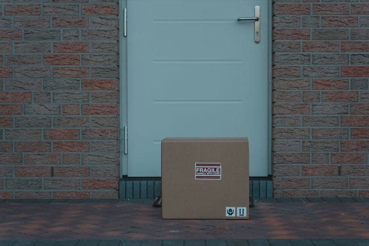 An unopened cardboard parcel marked fragile, waiting on a doorstep