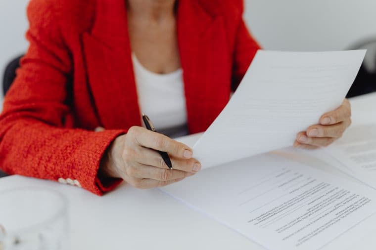 A person in a red jacket reviewing documents at a desk