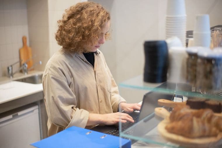 A sole trader working on a laptop behind a small business counter