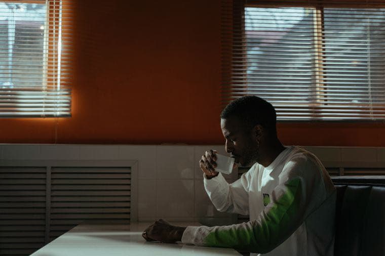 A person pausing over a coffee in a quiet diner