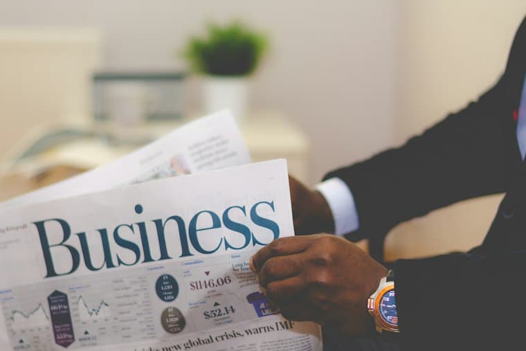A person in a suit reading the business section of a newspaper