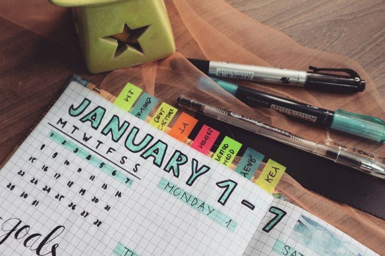 A goal-planning journal and marker pens on a desk