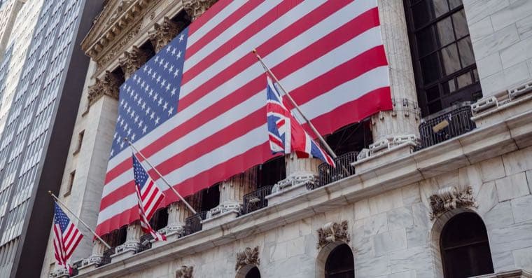 A US flag beside a rising stock market chart of big tech companies