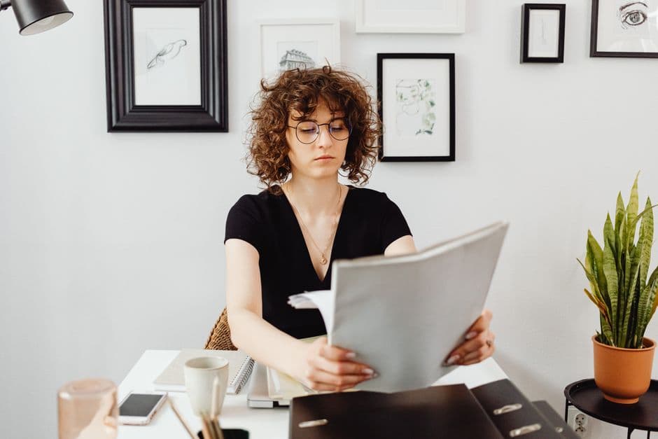A person reading a printed statement at a home desk