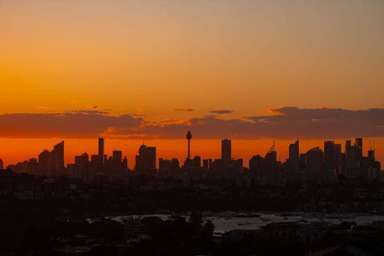 The Sydney skyline in silhouette against an orange sunset