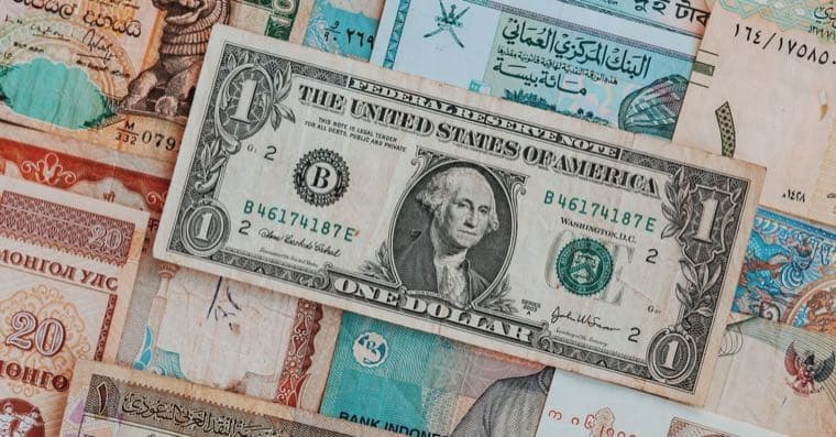 A stack of international banknotes topped with a US dollar bill